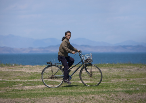 North Korean woman riding on a bicycle in the countryside, North Hamgyong Province, Chilbo Sea, North Korea