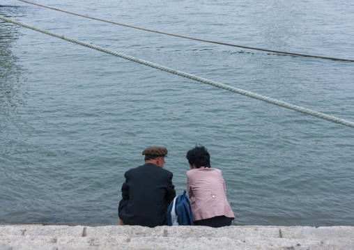North Korean couple sit in front of Taedong river, Pyongan Province, Pyongyang, North Korea