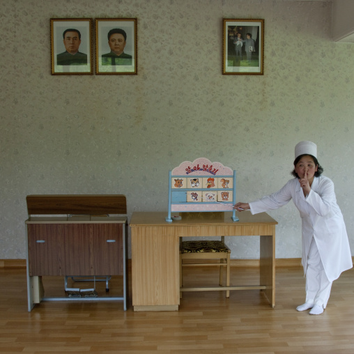 North Korean teacher under the official portraits of the Dear Leaders in a classroom in Kim Jong suk school, Pyongan Province, Pyongyang, North Korea