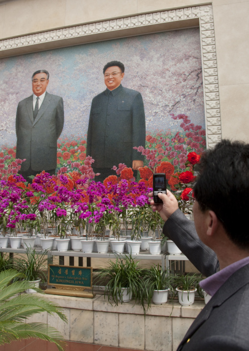 North Korean man taking a picture with his mobile phone at Kimilsungia and Kimjongilia exhibition, Pyongan Province, Pyongyang, North Korea