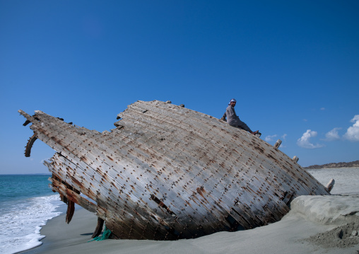 Man Sitting On The Wreck Of Dhow On The Beache, Masirah Island, Oman
