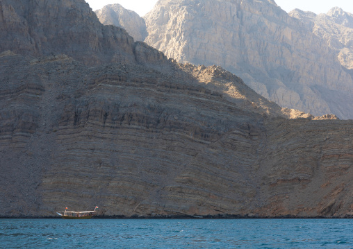 Dhow sailing in the fjords in front of mountains, Musandam Governorate, Khasab, Oman
