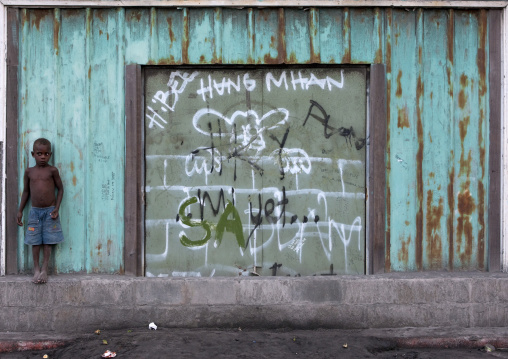 Boy in front of a closed shop, East New Britain Province, Rabaul, Papua New Guinea