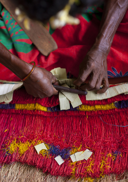 Woman making a traditional skirt with pandanus and banana leaves, Milne Bay Province, Trobriand Island, Papua New Guinea