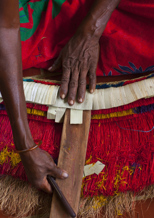 Woman making a traditional skirt with pandanus and banana leaves, Milne Bay Province, Trobriand Island, Papua New Guinea