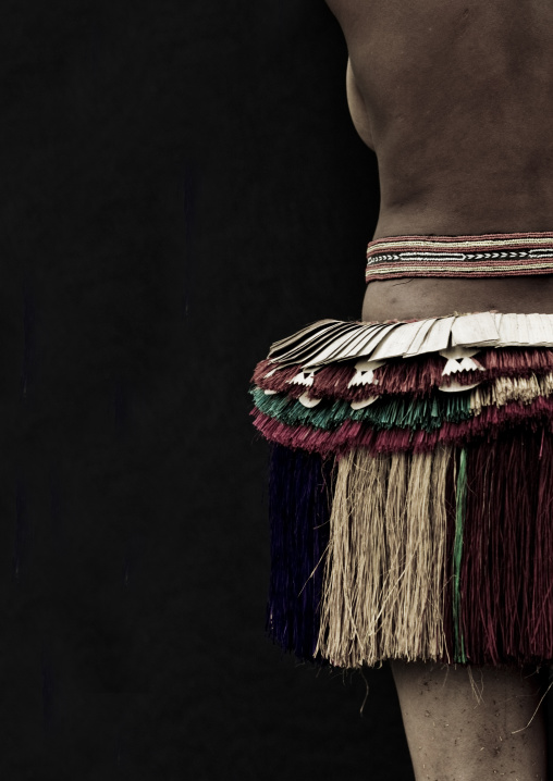 Woman wearing a traditional red skirt made with pandanus and banana leaves, Milne Bay Province, Trobriand Island, Papua New Guinea
