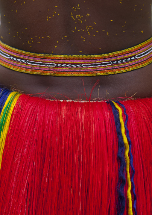 Woman wearing a traditional red skirt made with pandanus and banana leaves, Milne Bay Province, Trobriand Island, Papua New Guinea
