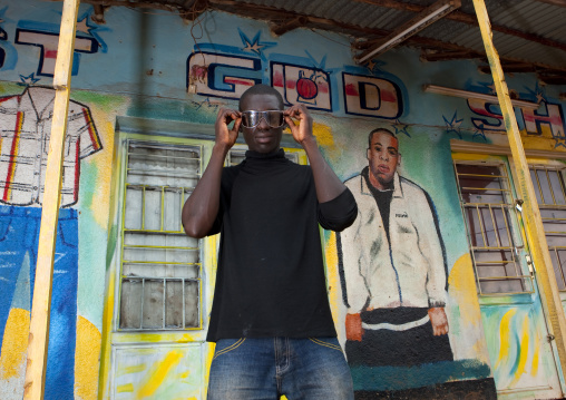 Rwandan man in front of a tailor shop mural, Kigali Province, Kigali, Rwanda