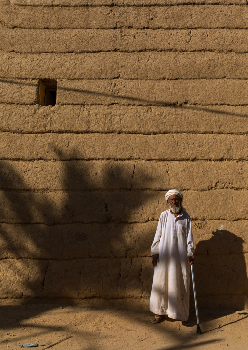 Old saudi man standing in front of a mud house, Najran Province, Najran, Saudi Arabia