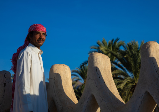 Saudi man standing on the crenelated terrace of his mud house, Najran Province, Najran, Saudi Arabia