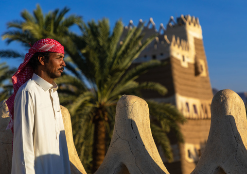 Saudi man standing on the crenelated terrace of his mud house, Najran Province, Najran, Saudi Arabia