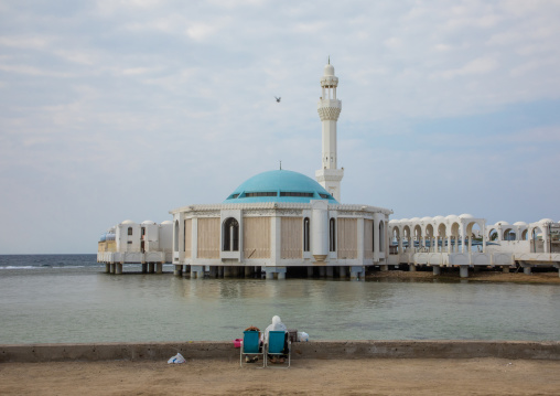 Saudi couple sitting in front of the floating mosque or masjid Bibi Fatima, Mecca province, Jeddah, Saudi Arabia