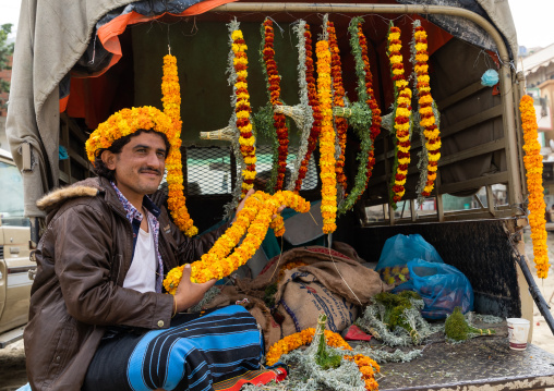 A flower vendor preparing floral garlands and crowns on a market in the back of his car, Jizan Province, Addayer, Saudi Arabia