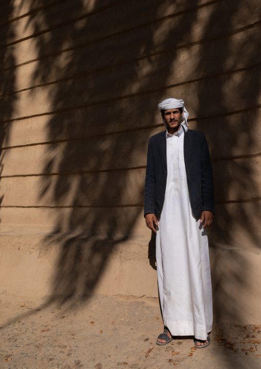 Saudi farmer standing in front of a traditional old mud house, Najran Province, Najran, Saudi Arabia