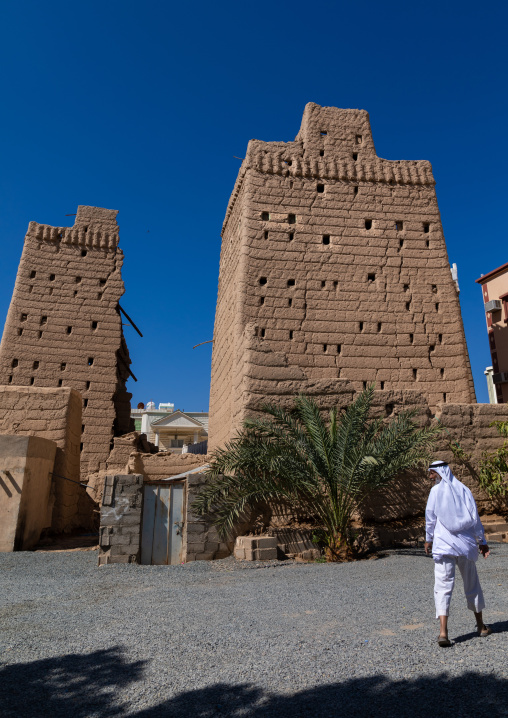 Saudi man passing in front of traditional old mud houses, Najran Province, Najran, Saudi Arabia