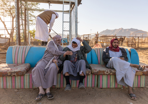 Saudi men resting on a sofa in the camel market, Najran Province, Najran, Saudi Arabia