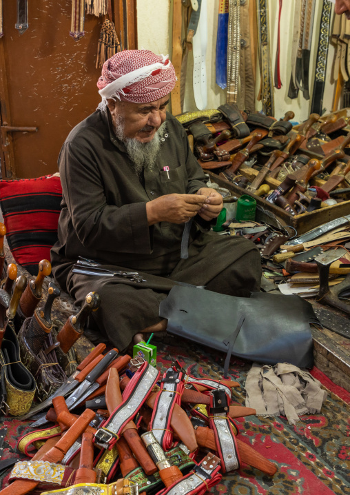 A saudi man prepares a traditional janbiya dagger for sale inside his shop, Najran Province, Najran, Saudi Arabia
