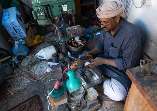 A saudi man prepares a traditional janbiya dagger for sale inside his shop, Najran Province, Najran, Saudi Arabia