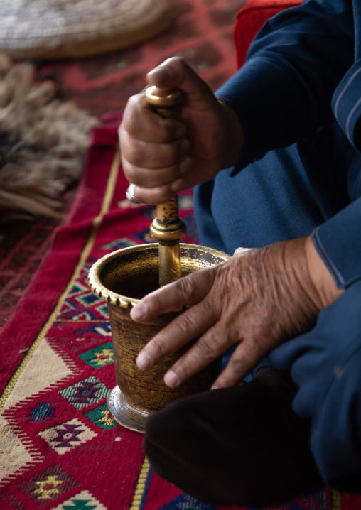 Saudi man preparing coffe with a pestle in a majlis, Asir province, Tanomah, Saudi Arabia
