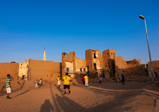 Saudi men playing football in the middle of old houses, Najran Province, Najran, Saudi Arabia