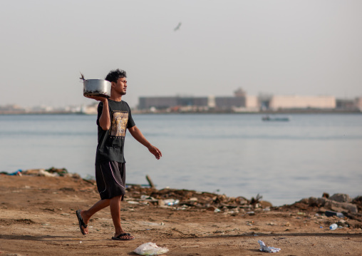 Asian foreign worker carrying fish, Jizan Region, Jizan, Saudi Arabia