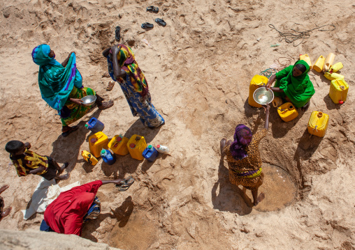 Somali women taking drinking water from a well hole in the sand and pouring it into plastic containers, North-Western province, Lasadacwo Village, Somaliland