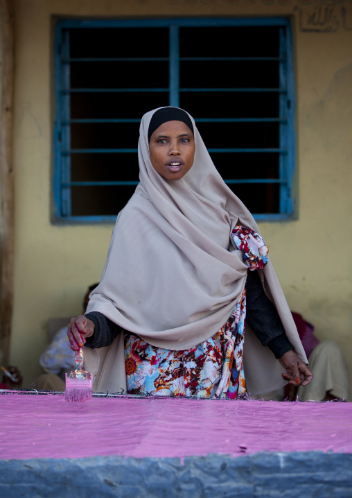 A Woman Wearing A Beige Hijab Painting A Fence In Pink,  Boorama, Somaliland