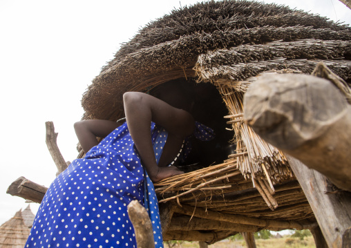 Toposa tribe girl climbing in a granary in a village, Namorunyang State, Kapoeta, South Sudan