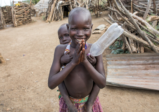 Smiling Toposa tribe girl carrying a baby in her back, Namorunyang State, Kapoeta, South Sudan