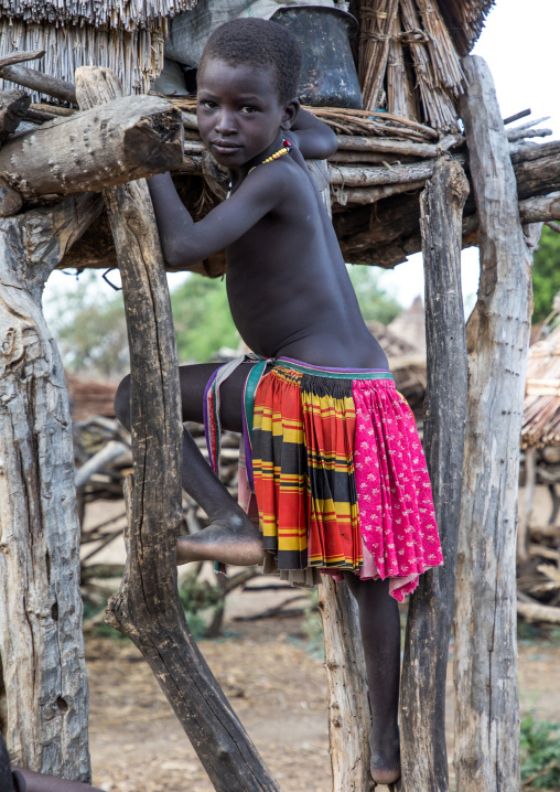 Toposa tribe girl climbing in a granary in a village, Namorunyang State, Kapoeta, South Sudan