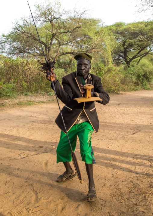 Toposa tribe man dancing with a spear and a wooden seat, Namorunyang State, Kapoeta, South Sudan