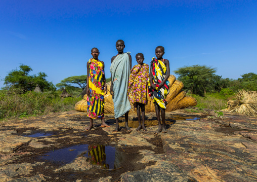 Larim tribe girls in front of thatch used to make the houses roofs, Boya Mountains, Imatong, South Sudan