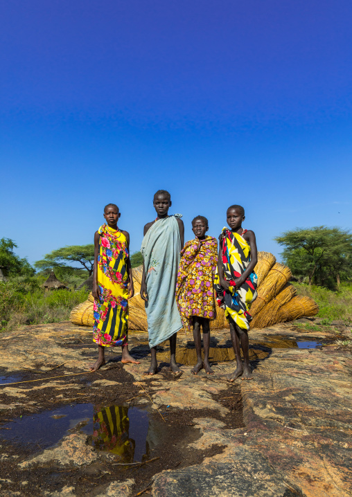 Larim tribe girls in front of thatch used to make the houses roofs, Boya Mountains, Imatong, South Sudan