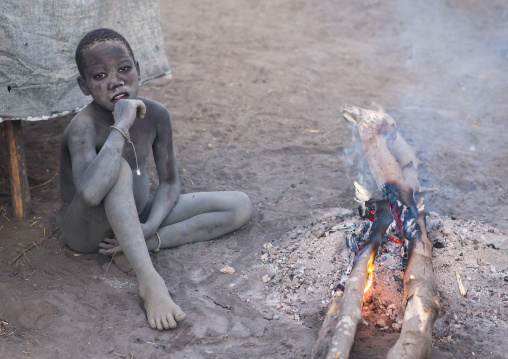 Mundari tribe boy making a campfire with dried cow dungs to repel flies and mosquitoes, Central Equatoria, Terekeka, South Sudan