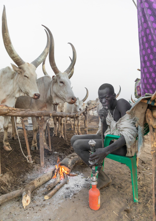 Mundari tribe man smoking shisha in a cattle camp, Central Equatoria, Terekeka, South Sudan