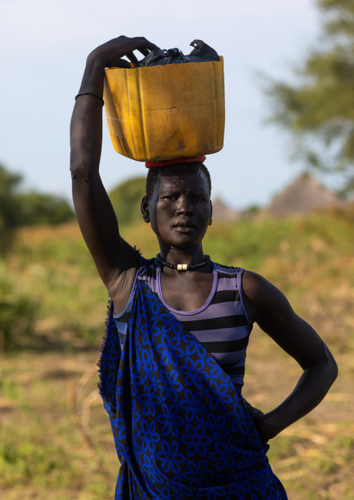 Portrait of a Mundari tribe woman with scarifications on the forehead carrying a jerrican, Central Equatoria, Terekeka, South Sudan