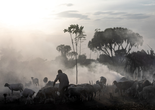 Mundari tribe boy taking care of the bonfires made with dried cow dungs to repel flies and mosquitoes, Central Equatoria, Terekeka, South Sudan