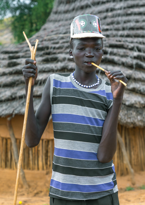 Larim tribe boy with a fashionnable look using a wooden toothbrush, Boya Mountains, Imatong, South Sudan