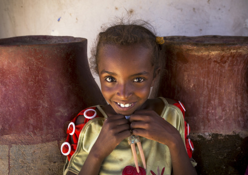 Sudan, Northern Province, Gunfal, smiling sudanese girl in front of water jars