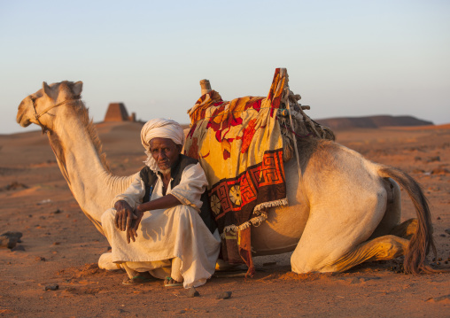 Sudan, Kush, Meroe, man and his camel in front of the pyramids and tombs in royal cemetery