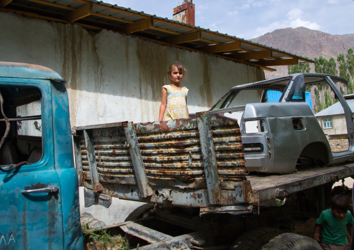 Tajik girl playing in old cars wrecks, Gorno-Badakhshan autonomous region, Khorog, Tajikistan