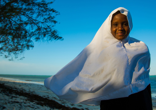 Tanzania, Zanzibar, Kizimkazi, young muslim girl in school uniform running on beach