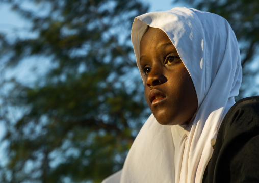 Tanzania, Zanzibar, Kizimkazi, young muslim girl in school uniform running on beach