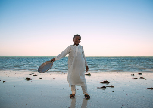 Tanzania, Zanzibar, Kizimkazi, young muslim boy in school uniform on beach