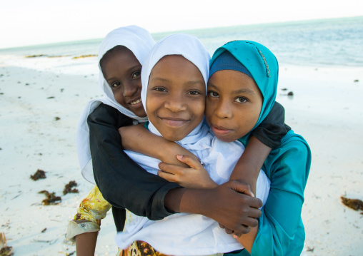 Tanzania, Zanzibar, Kizimkazi, young muslim girls in school uniform running on beach