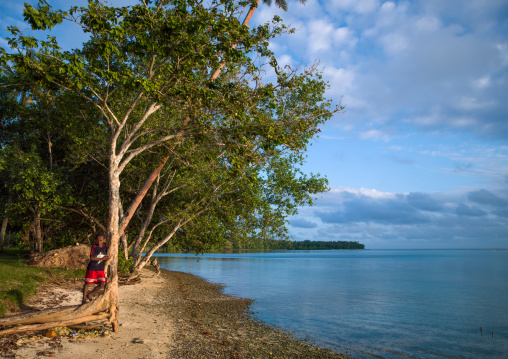 Boy standing in front of a turquoise water and white sand on Erakor beach, Shefa Province, Efate island, Vanuatu