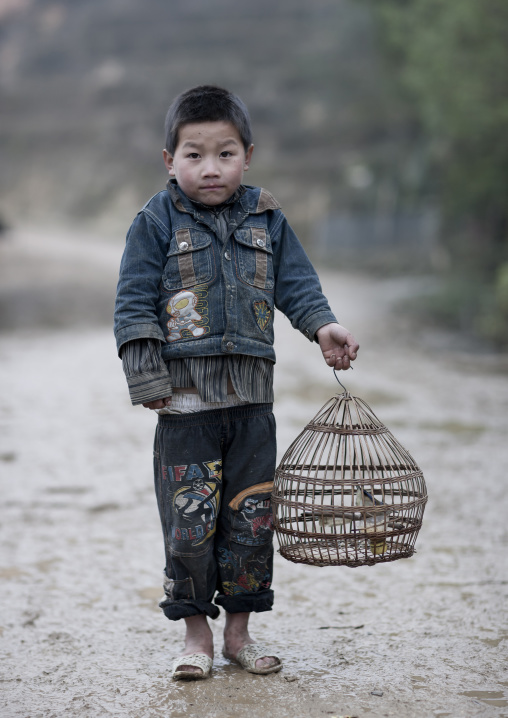 Black hmong boy holding a caged bird, Sapa, Vietnam