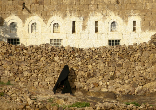 Veiled Woman In Black Passing By A Stone Wall, Shahara, Yemen