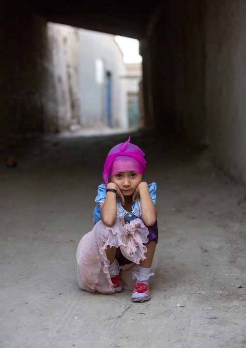 Uyghur girl squatting alone in the street, Yarkand, Xinjiang uyghur autonomous region, China