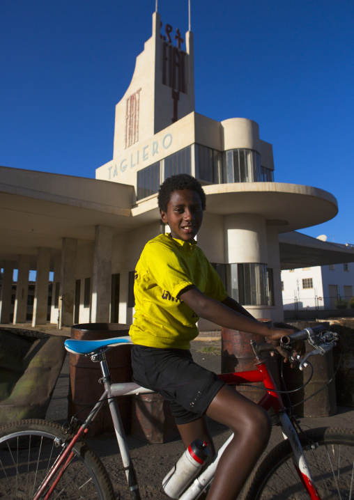 Eritrean boy on a bicycle near Fiat tagliero garage and service station, Central Region, Asmara, Eritrea